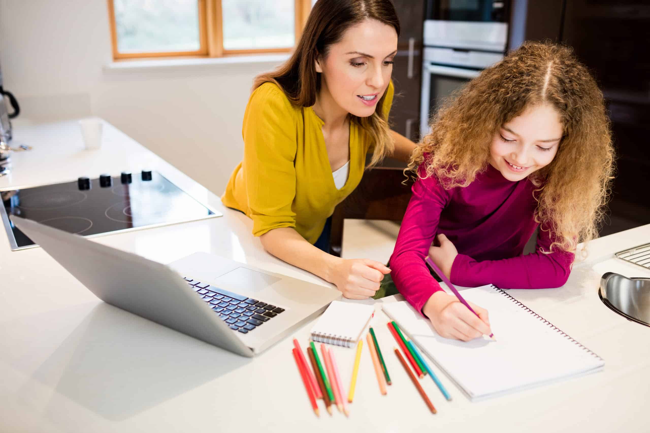 Mother and daughter helping daughter with her homework Mother and daughter helping daughter with her homework in kitchen